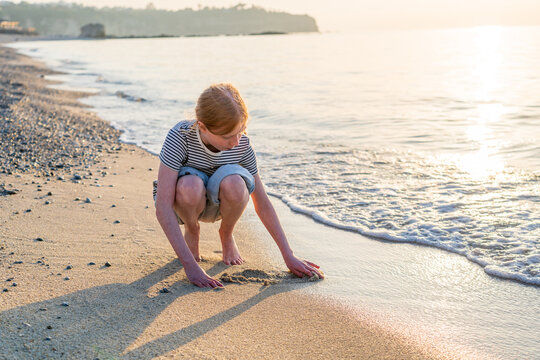 Girl playing in the sand on the beach during golden hour