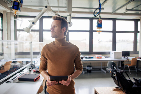 Engineer wearing turtleneck and holding tablet PC at workshop