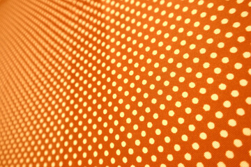 Fototapeta premium Vibrant orange fabric with a dense repeating pattern of small white polka dots in perspective