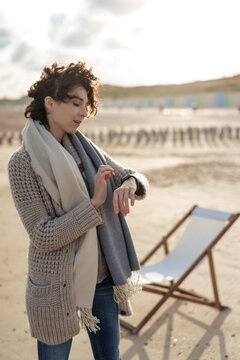 Woman wearing cardigan sweater checking time standing at beach