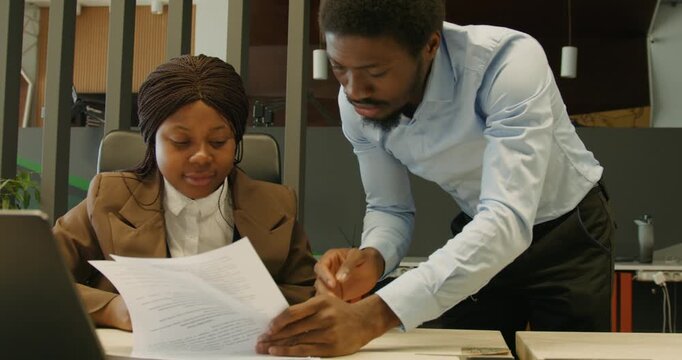 Leader cooperates with junior personnel reviewing legal papers at workplace