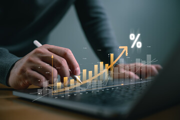 Naklejka premium Businessman hand using stylus pen on laptop with glowing rising growth graph and percentage icon. Concept of business success, financial profit, interest rate increase, and data analysis.