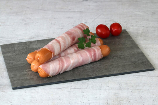  Berner W&uuml;rstchen. Mit Speck ummantelte Grillw&uuml;rstchen auf Schieferplatte in Steinoptik