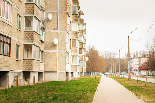 typical residential district with soviet panel apartment building and paved walkway leading into distance under spring sky