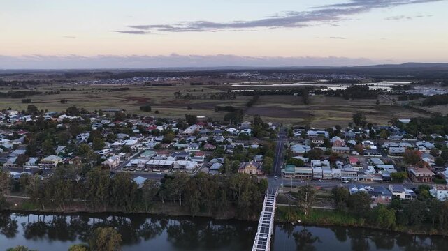Aerial video flying over Morpeth bridge and Hunter River toward historic Morpeth township in NSW, Australia. Scenic landscape showing river crossing, rural surroundings and heritage town setting.