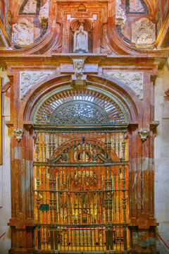 Interior of Mosque Cathedral of Cordoba, Spain. Ornate metal grille and Madonna sculpture above the altar, indoor light