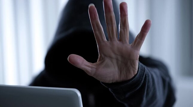 Don't disturb: a hacker gestures asking avoid verbal contact as they are hacking the site