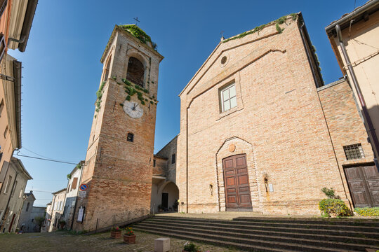 Historic brick fa&ccedil;ade and bell tower of the Church  San Michele Arcangelo in Mondaino, Emilia Romagna, Italy, illuminated by morning sunlight under a clear blue sky