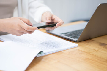Fototapeta premium Businesswoman Using Smartphone While Reviewing Documents at Desk