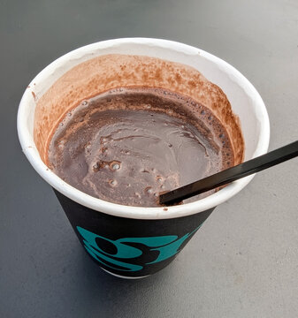 Hot chocolate with bubble in disposable paper cup isolated on black background.