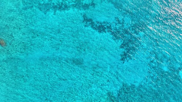 Vast blue ocean background with moderate waves, looking straight down. Blue seawater texture, aerial view. Abstract background of water flowing under the influence of light. Blue lagoon surface.