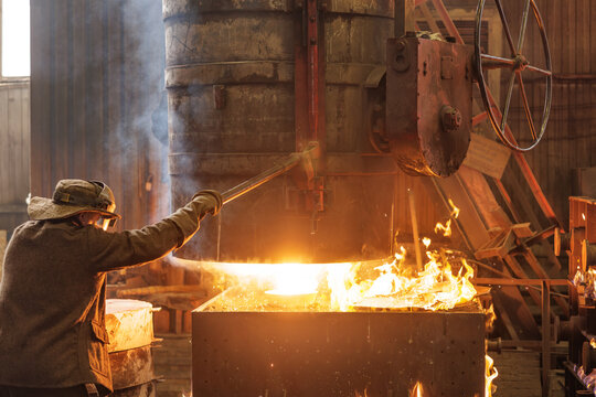 Worker handling molten metal in casting mold