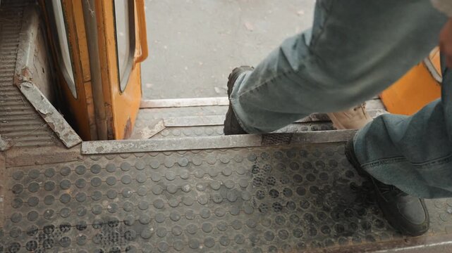 Closeup feet boarding vintage bus steps, jeansclad passenger stepping onto worn threshold, scuffed shoes on diamondplate treads, hurried urban commute captured by creator filmmaker, candid transit
