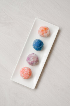Top View of Four Colorful Mochi Balls Arranged on White Plate