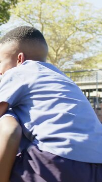 Vertical video: Starting piggyback, boys giving friend ride at school recess, wearing uniforms