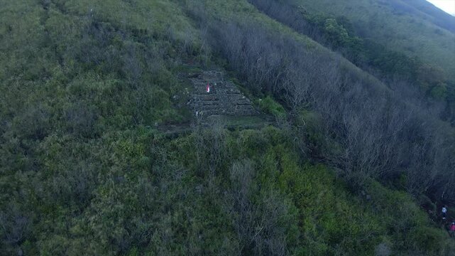 4K Aerial View of Ancient Stone Temple Ruins on the Lush Green Slopes of Mount Penanggungan in Indonesia.