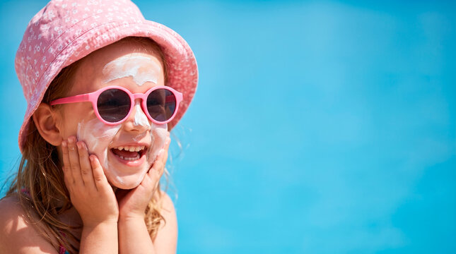 Happy child with sunscreen on face wearing sunglasses and hat outdoors