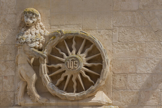 Gothic stone relief of a lion holding a wheel with IHS monogram at Burgos Cathedral, Spain