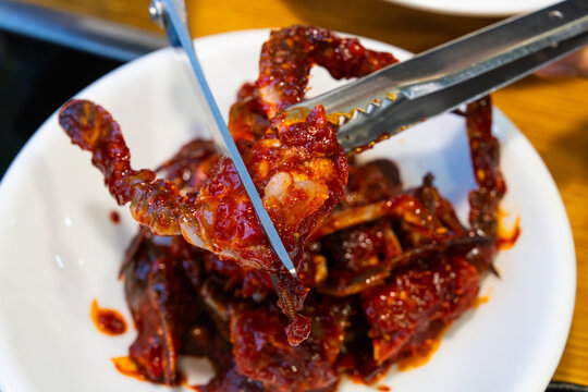 Cutting Spicy Marinated Raw Crab with Kitchen Scissors in Korean Restaurant