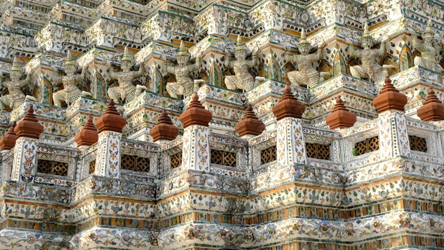 Intricate craftsmanship of Temple of Dawn (Wat Arun) featuring mythical giant figures and colorful ceramic tile decorations, historic landmark in Bangkok.