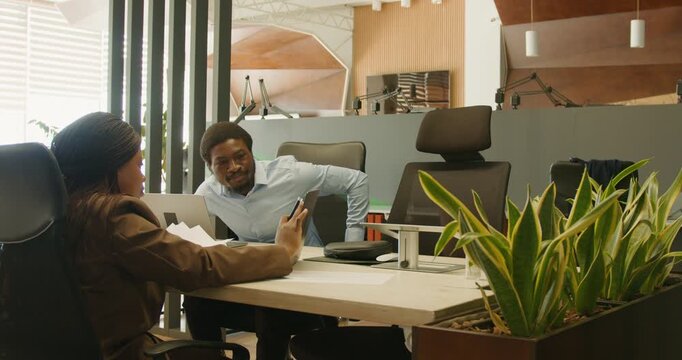 Engaged conversation characterized by animated gestures and indoor greenery