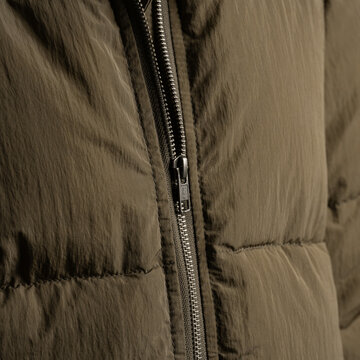 Dnepr, UKRAINE 11.04.2024 : Close-up of a high-quality metal YKK zipper on a brown olive textile jacket. Detailed view of the slider and teeth, showcasing garment manufacturing standards.
