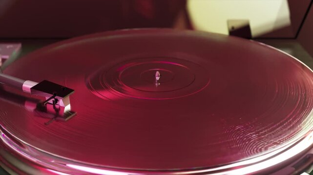 Red vinyl record spinning on a classic turntable with a stylus tracking the grooves in a close-up shot, capturing the retro atmosphere of analog music and hi-fi audio equipment