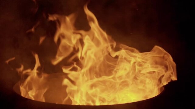 Cinematic 4K vertical shot of intense, roaring fire pit flames isolated against a pure black background. Perfect for social media formats and VFX blending modes.