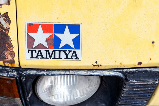 Nonthaburi, Thailand - 23 April 2026: Closeup of Tamiya logo sticker above headlight of on weathered yellow vintage van car front with cracked paint and heavy rust. showing authentic patina and wear.