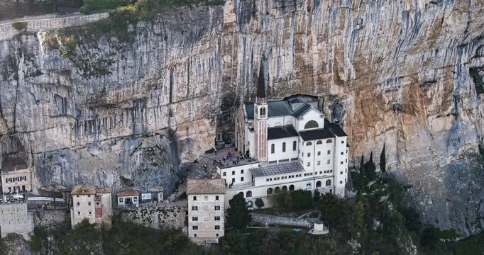 Aerial hyperlapse view of Santuario Madonna della Corona, a cliffside Catholic sanctuary and popular pilgrimage site in Italy.