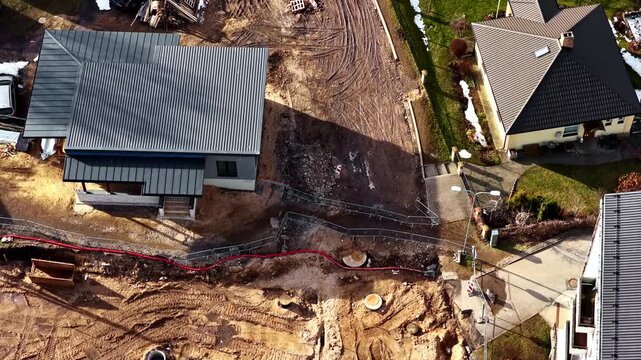 Excavation site preparing for pipelines and foundation alongside residential homes