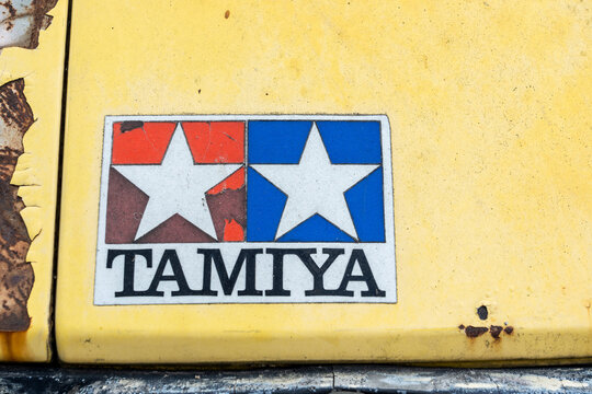Nonthaburi, Thailand - 23 April 2026: Closeup of Tamiya logo sticker above headlight of on weathered yellow vintage van car front with cracked paint and heavy rust. showing authentic patina and wear.