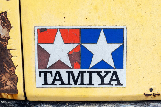 Nonthaburi, Thailand - 23 April 2026: Closeup of Tamiya logo sticker above headlight of on weathered yellow vintage van car front with cracked paint and heavy rust. showing authentic patina and wear.