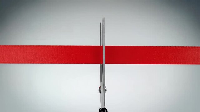 Scissors cutting red ribbon in half, studio shot with copy space for grand opening event promotion