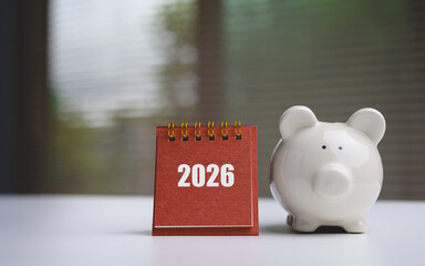 2026 financial planning and saving money concept with red calendar and white piggy bank on desk. © Ohayo