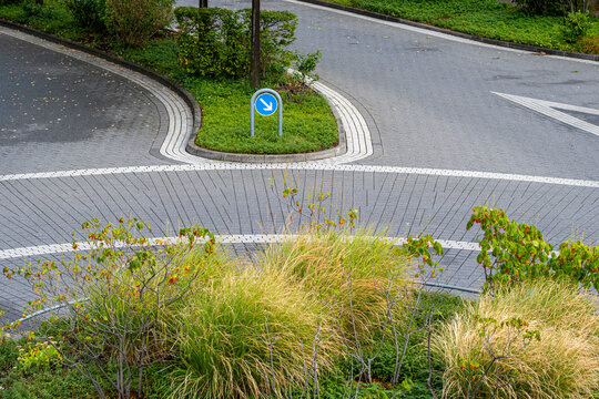 Empty urban road intersection with curve curb and asphalt showing traffic sign infrastructure and minimal geometry in a quiet street scene