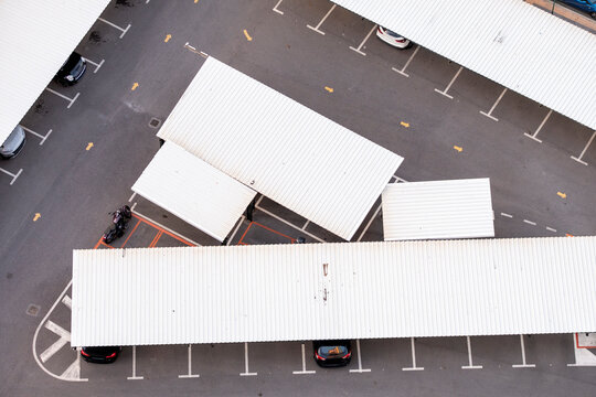 Aerial urban geometry pattern of parking carport rooftops and structure with lines framing vehicles in a clean modern topview layout