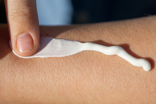  sunscreen cream skin protection hand applying white lotion on arm close up for sun safety concept of skincare, dermatology, and summer wellness with copy space for banner design
