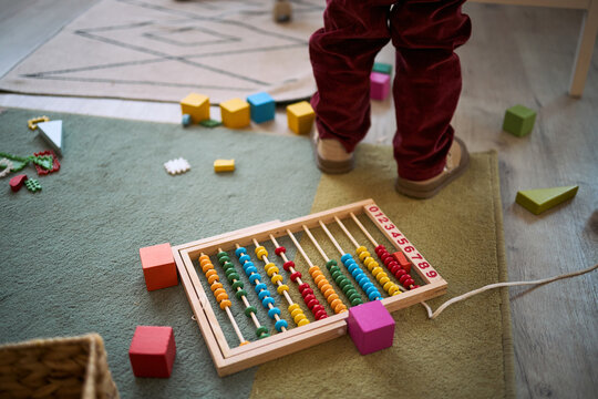 Close up of child stepping near abacus and blocks on floor, engaging in early math play and motor learning