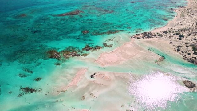 Top down aerial of Elafonisi pink sand beach and turquoise water shades. Drone view of exotic shallow lagoon with crystal clear sea and tropical look in Crete, Greece. Mediterranean paradise, 4k.
