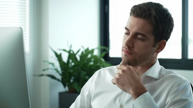 Young caucasian man in crisp white shirt at modern office desk, focused, then shifts to boredom and fatigue, natural light, blurred office. Concept of workplace burnout