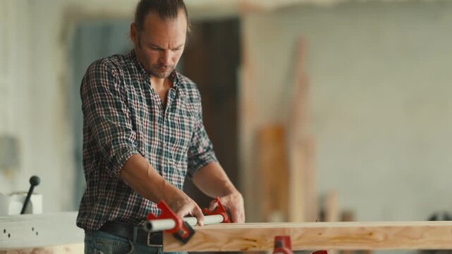 Professional carpenter gluing and clamping wood planks