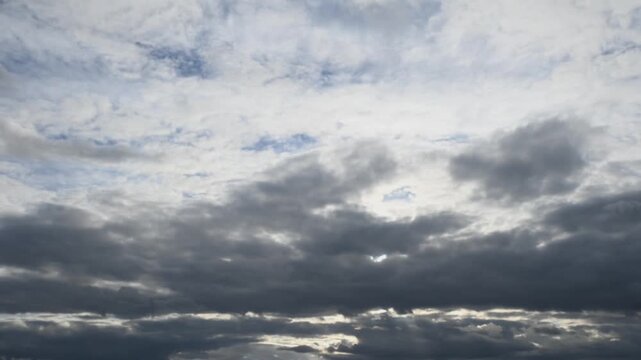 Observers watch the sky changes before sunset. The clouds shift and colors alter from bright to dark, capturing the passing time and movement in the sky