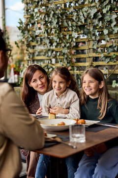 Mother and Two Daughters Smiling Together Over Lunch at a Cafe Terrace During Family Brunch