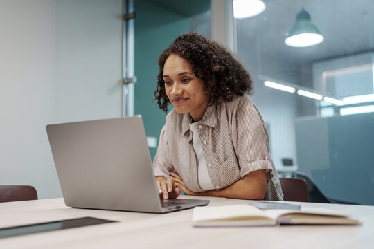 Concentrated Woman Working. Woman Examining Design Materials On Her Laptop In Professional Setting