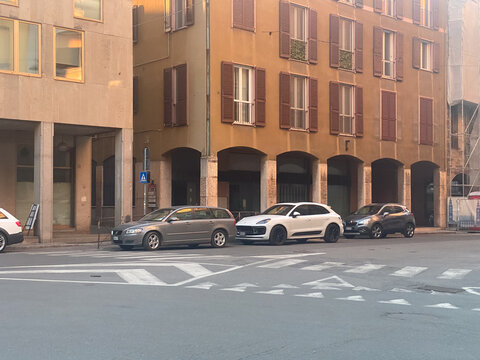 Urban street scene featuring a Volvo V50, Porsche Macan, and another SUV parked along an architectural facade in Italy