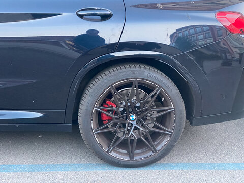 BMW X4 M competition black SUV showing wheel, tire, red brake caliper and scratched body panel