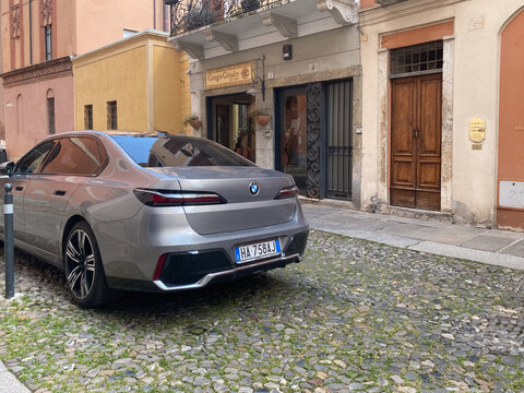 BMW i7 electric luxury sedan parked on cobblestone street in Cremona, Italy, by Giorgio Grisales violin maker shop