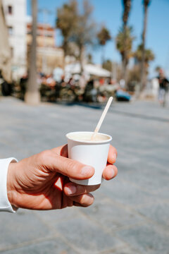 a man holds a cortado in a paper cup