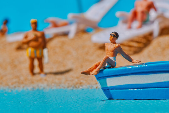 a miniature man leaning on a blue boat